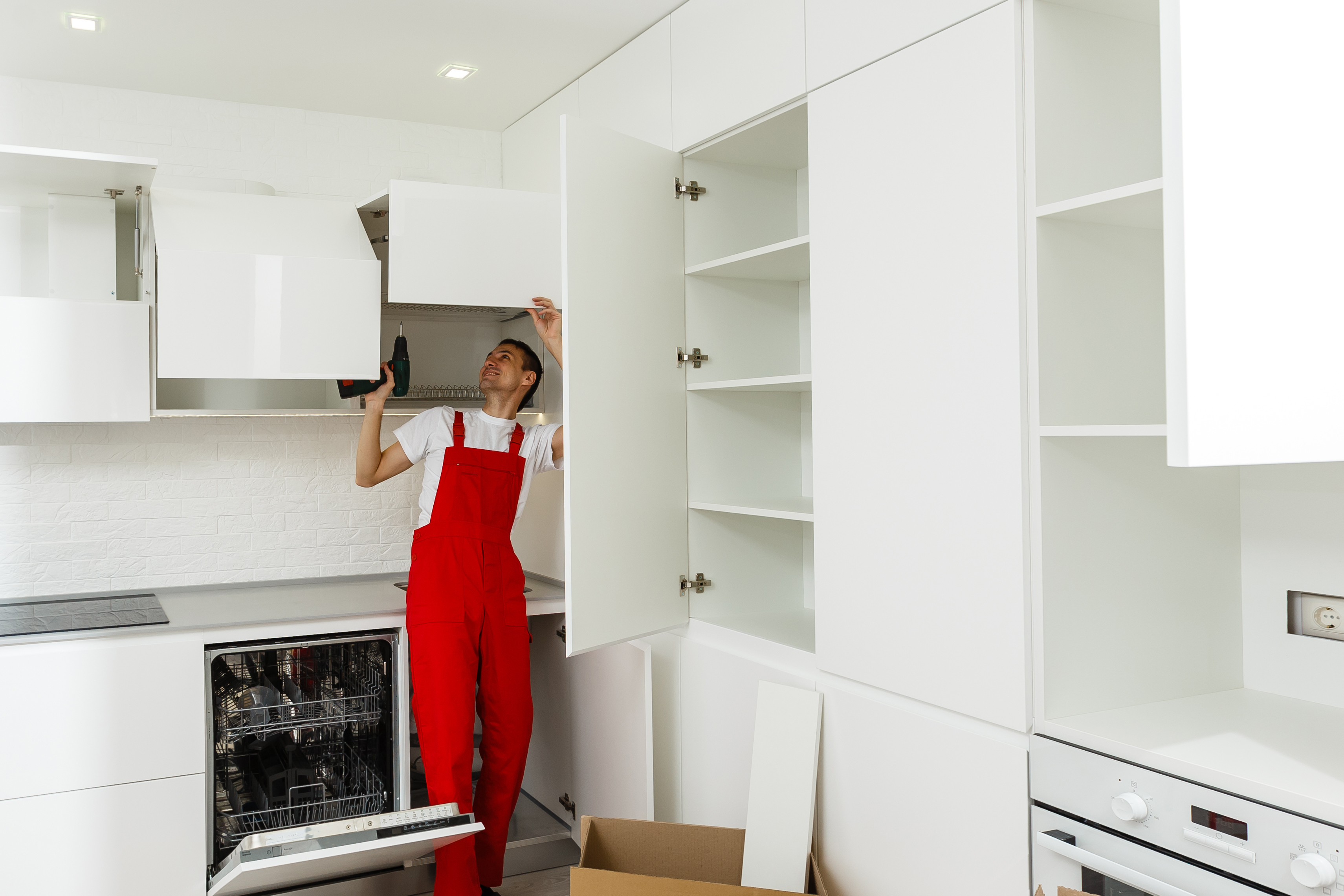 Handyman fixing kitchen s cabinet with screwdriver